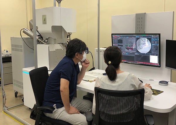 東陽テクニカナノイメージングセンターでXeプラズマFIB-SEMを使用し分析している様子（左が中村先生）